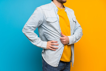 Handsome over isolated colorful background suffering from backache for having made an effort