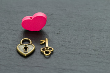 Heart-shaped padlock with key on a slate stone background . key from heart concept
