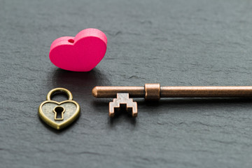 Heart-shaped padlock with key on a slate stone background . key from heart concept