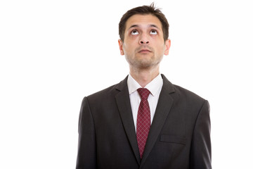 Studio shot of young businessman thinking while looking up 