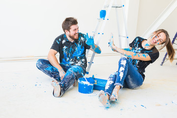 People, redecoration and relationship concept - Young funny couple doing renovation in new...