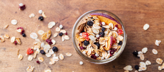 Granola, muesli in glass jar. Healthy breakfast. Organic oats with apples, berries and nuts. Top view.