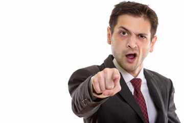 Studio shot of angry young businessman pointing at camera 