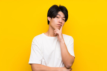 Asian man over isolated yellow wall Looking front