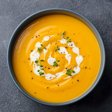 Pumpkin, carrot cream soup in a bowl. Slate background. Close up. Top view.
