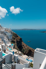 Fototapeta na wymiar Santorini, Greece. Picturesque view of traditional cycladic Santorini houses on small street with flowers in foreground. Location: Oia village, Santorini, Greece. Vacations background.