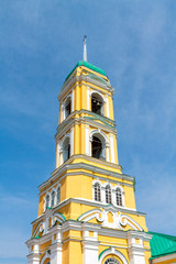 Obraz premium Yellow Orthodox Christian church with a green dome in summer against a blue sky with white clouds.