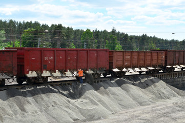 Unloading of crushed stone from railway car. Unloading bulk cargo from railway wagons on of high railway platform. Work with bulk cargo.