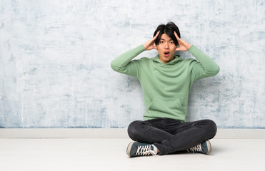 Asian man sitting on the floor with surprise expression