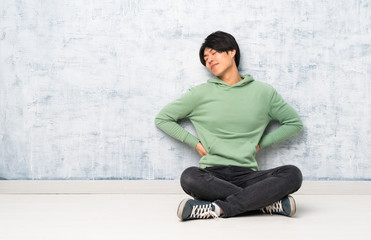 Asian man sitting on the floor suffering from backache for having made an effort