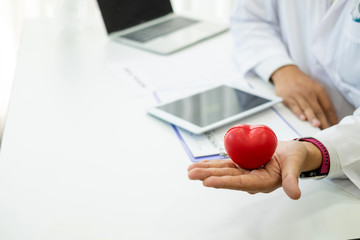 Male doctor holding a red heart. Health care concept Heart disease treatment.