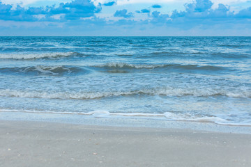Fototapeta na wymiar The blue sea creates waves by the white sea breeze blowing into the shore.