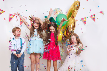 Group of kids throwing colorful confetti and looking happy on birthday party