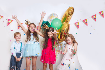 Group of kids throwing colorful confetti and looking happy on birthday party