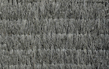 The wall of the old house is fortified with dry grass of gray color .Texture or background.