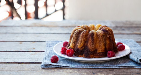 Chocolate marble bundt cake with raspberry on wooden background. Copy space.