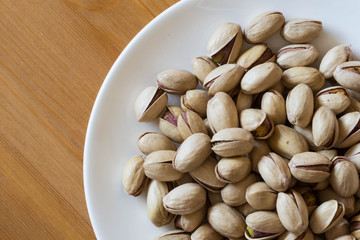Pistachios in a white saucer container plate ready to be served and eaten. 