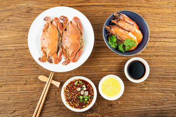 A dish of steamed three-pointed crab and sauce on a wooden table