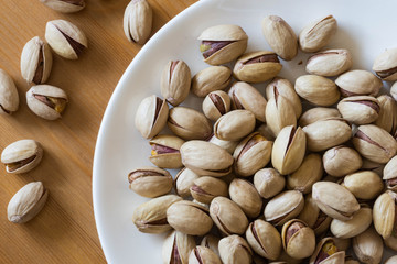 Pistachios in a white saucer container plate ready to be served and eaten. 