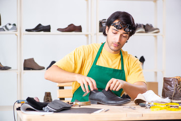 Young man repairing shoes in workshop 