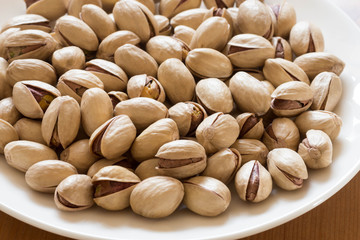 Pistachios in a white saucer container plate ready to be served and eaten. 