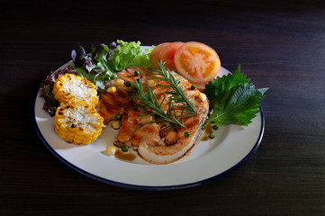 Grilled salmon steak with tariyaki sauce in white dish on dark background