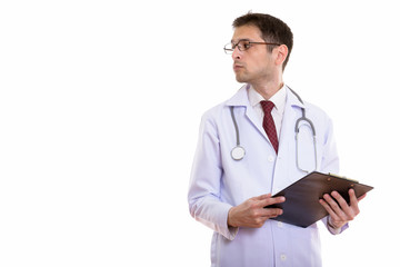 Fototapeta premium Profile view of young man doctor holding clipboard while looking