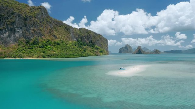 Aerial drone circling footage of sandbar form distance. Beautiful Lagen Island and white clouds moving in background. El Ndio, Palawan, Philippines