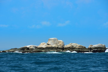 The background of a large rocky island in the blue sea and a blue sky