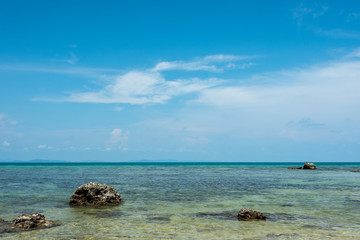 Clear sea, white sand beach, rocks in the sea and blue sky