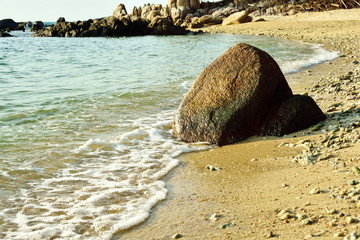 Clear sea, white sand beach, rocks in the sea and blue sky