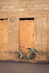 Green bicycle next to an old brick door