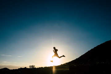 beautiful silhouette of teeenager or man running alone and doing a fit session in mountain with sunset - positive lifestyle - caucasian 20s guy