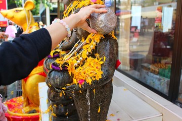  The girl is pouring water on a statue with yellow marigolds for fortune