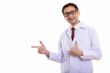 Studio shot of happy young man doctor smiling while pointing to 