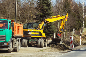 Excavator delivers construction waste to the truck. Cleaning the site for new construction. Construction works. Landscape design and layout of the city. Heavy machines facilitate the work of man