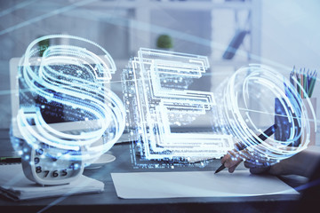 Multi exposure of woman's hands making notes with SEO icon. Concept of Search engine optimization