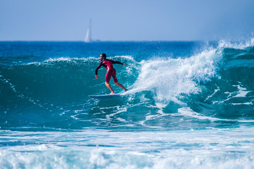 teenager surfing at the wave in tenerife playa de las americas - red wetsuits and beautiful and perfect wave