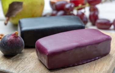 Mini black and dark red waxed cheddar cheeses made from West Country milk and and age-old methods in England