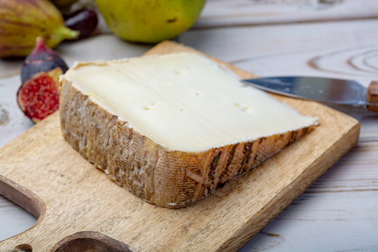 Piece of French cheese Tomme de Brebis made from sheep milk served as dessert with fresh figs and pears