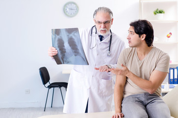 Obraz premium Young man visiting old male doctor radiologist 