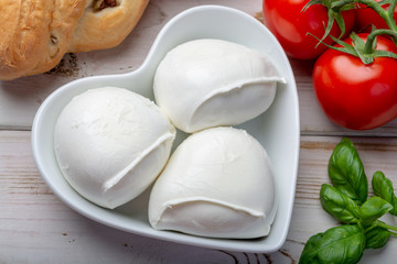 Love mozzerella, balls of buffalo mozzarella, soft Italian scheese made from the milk of Italian Mediterranean buffalo in heart shaped plate
