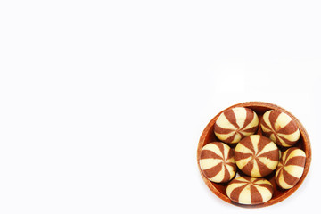 striped yellow brown chocolate chip cookies in a brown wooden plate on a white background