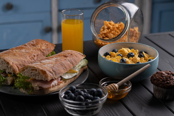 Food. Breakfast. Homemade delicious corn flakes with fruit and honey, baguette on black table on kitchen