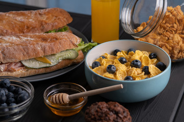 Breakfast. Traditional lunch. Snack. Baguette and fresh corn flakes with berry and muffin on black background. Kitchen