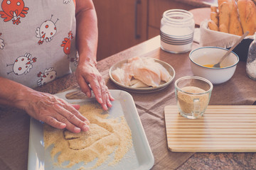 senior alone at home cooking fish at the kitchen -  very focused indoor - mature and caucasian 60s woman - retired woman