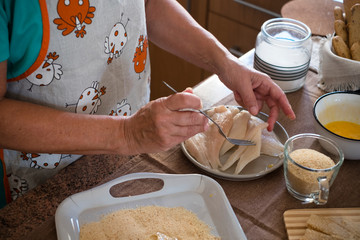 senior alone at home cooking fish at the kitchen -  very focused indoor - mature and caucasian 60s woman - retired woman