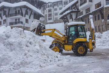 Yellow excavator, tractor with snowplow removing snow after heavy snowfall.. Winter time...