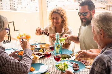 beautiful family sitting around the table full of food and drinks life vine, bread and meat - daughter, son grandma and grandpa celebration - couple of married celebration with the fathers 