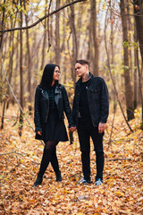 The girl and the guy are walking in the autumn forest